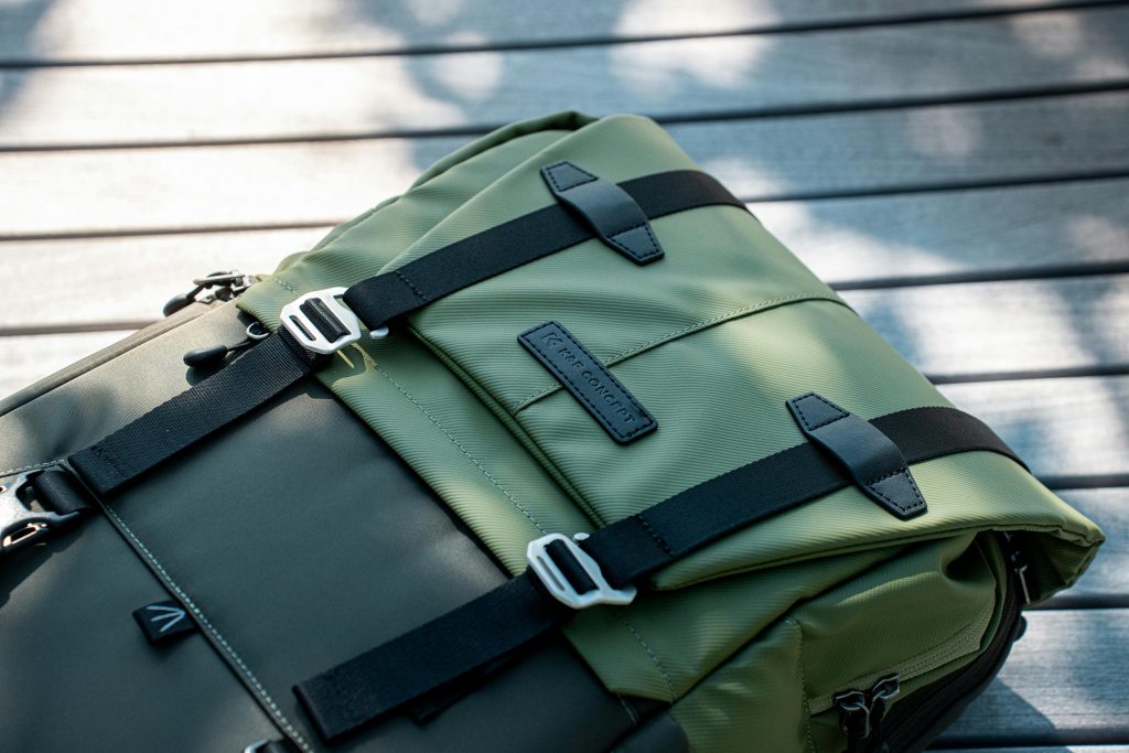 Close-up of a modern olive green backpack with black straps on a wooden surface, perfect for outdoor adventures.